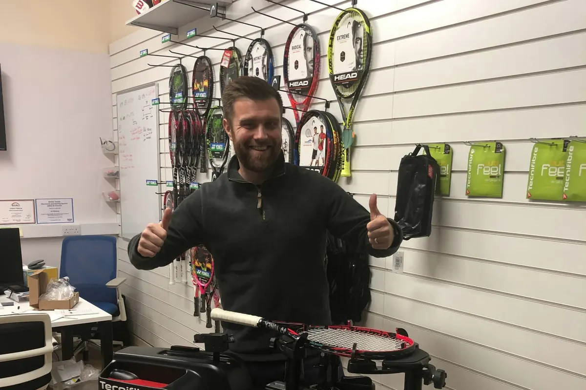 Ed giving a thumbs up behind a Tecnifibre stringing machine