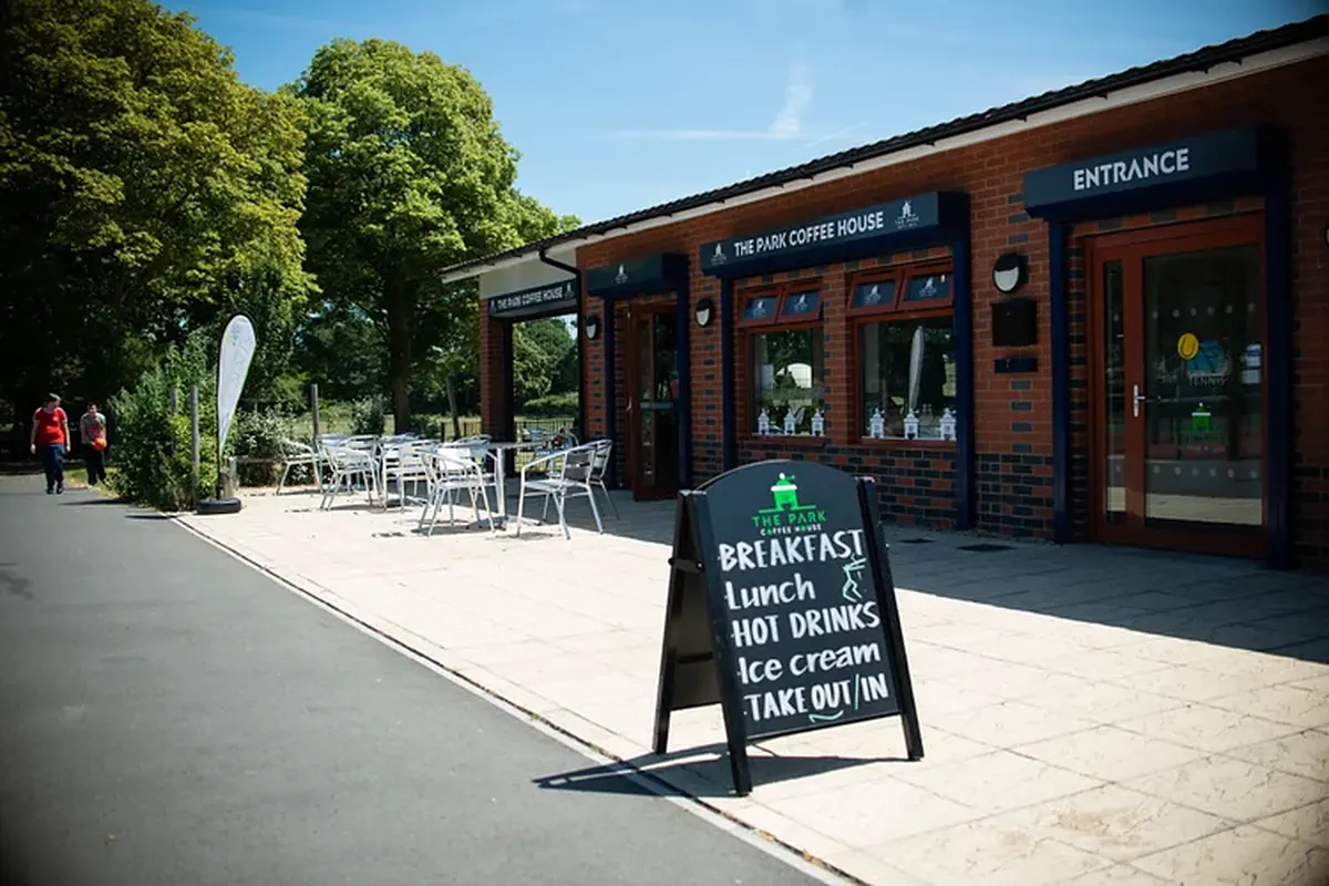 The Park Coffee House frontage at the Swindon tennis centre, with an A-board and outdoor tables