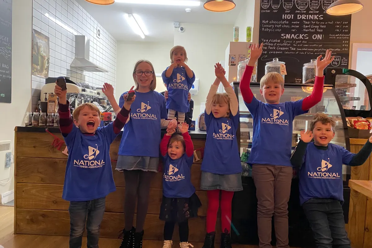 Children in National Tennis T-shirts cheering at the café counter