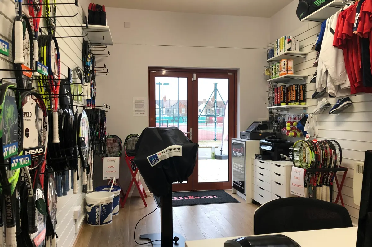 Inside The Racket Factory shop with rackets on the walls and courts through the door