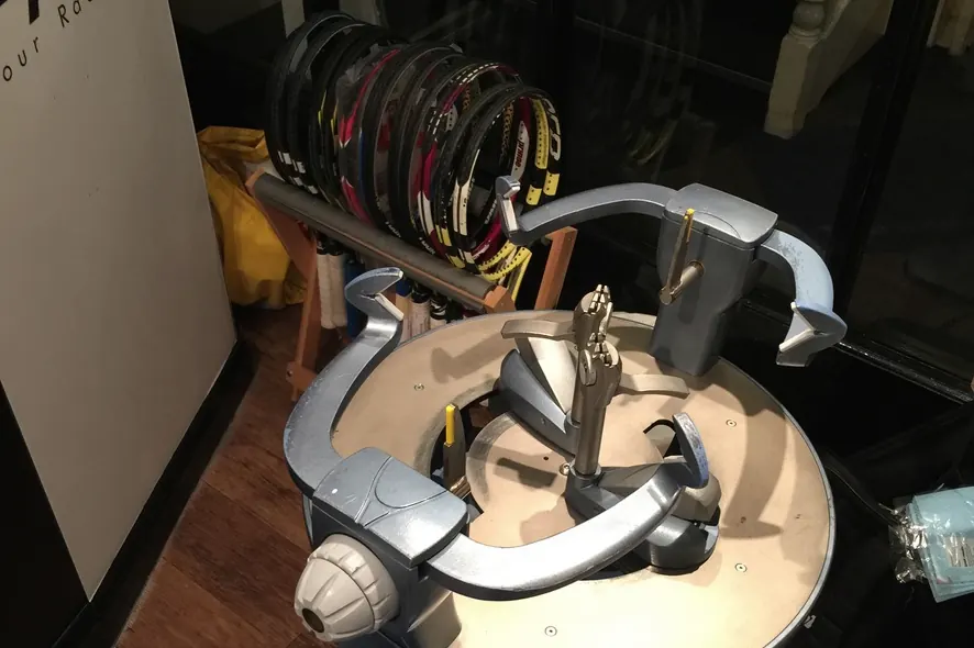 A racket stringing machine in front of a rack of rackets