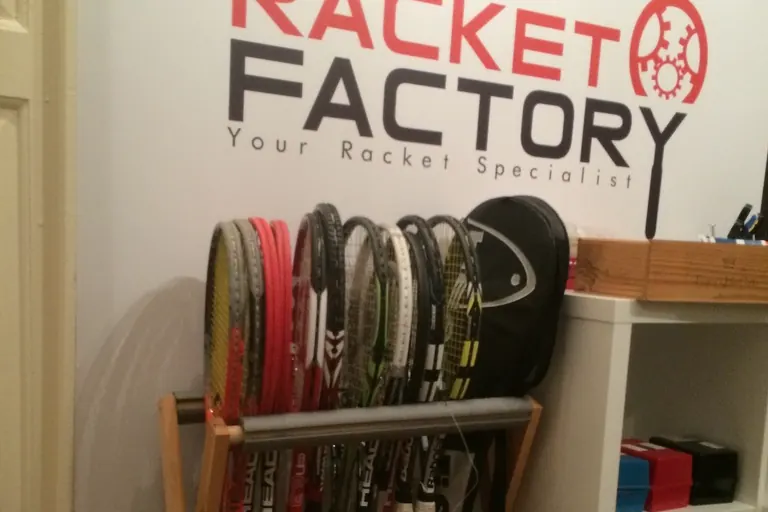 Rackets on a stand beneath The Racket Factory sign